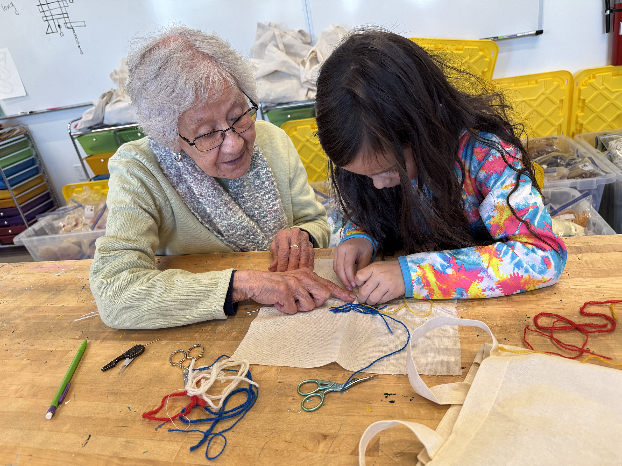 Artist Patsy Garcia shares the traditional colcha stitch with a Mountain Valley School 1st grade student.